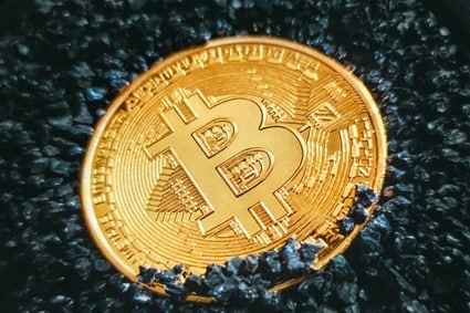 image showing a single Bitcoin surrounded by black stones